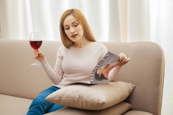 Vacker kvinna med ett glas vin och magazine — Stockfoto