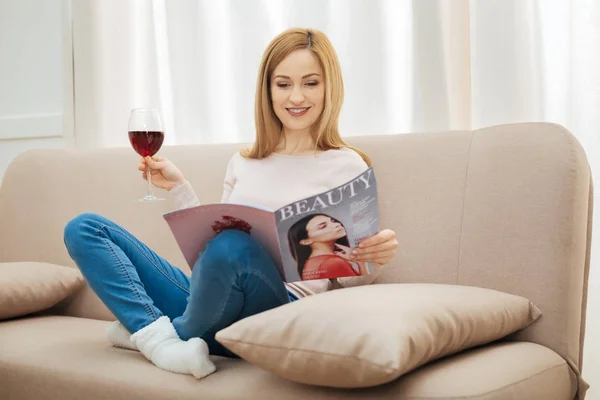 Smiling woman looking through a fashion magazine — Stock Photo, Image