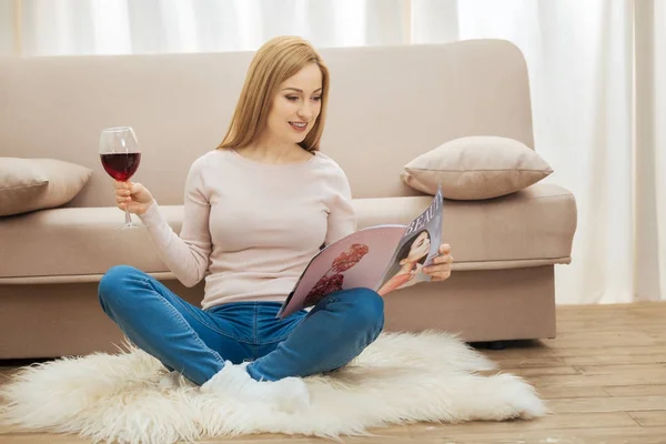 Веселая женщина сидит на полу с бокалом вина — стоковое фото