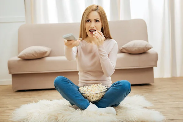 Mujer hermosa y contenta comiendo palomitas de maíz en el suelo — Foto de Stock