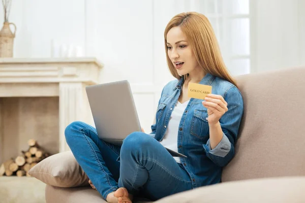Surprised woman holding a card and looking at the screen — Stock Photo, Image
