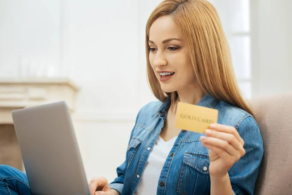 Mujer bastante sonriente sosteniendo una tarjeta de oro — Foto de Stock