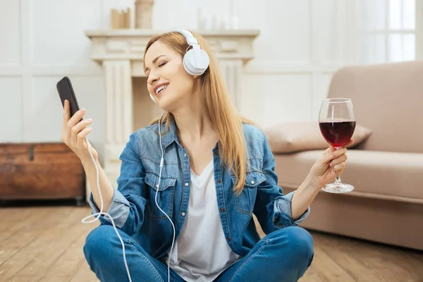 Mujer exuberante escuchando música con una copa de vino —  Fotos de Stock