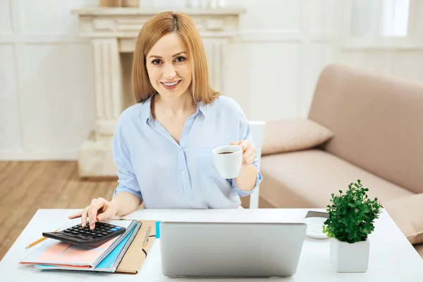 Cheerful woman holding a cup of tea while working — Stock Photo, Image
