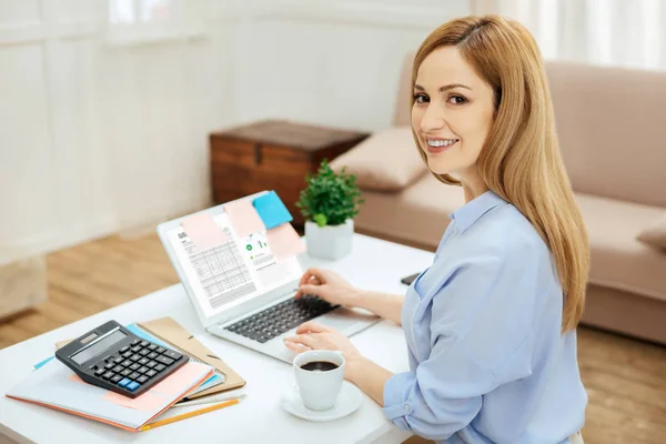 Mujer sonriente trabajando en su portátil desde casa — Foto de Stock