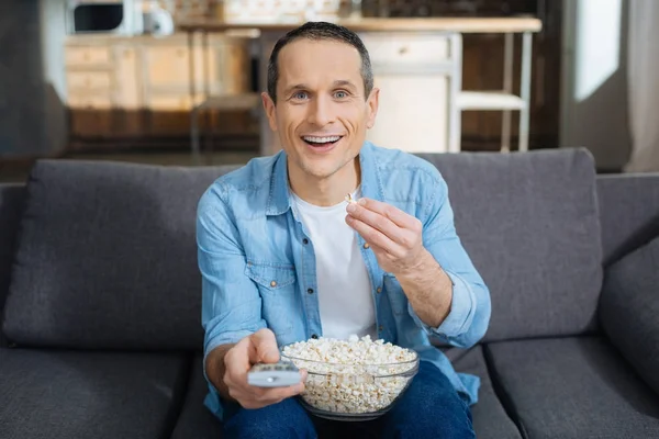 Fröhliche Brünette sitzt auf seinem Sofa — Stockfoto