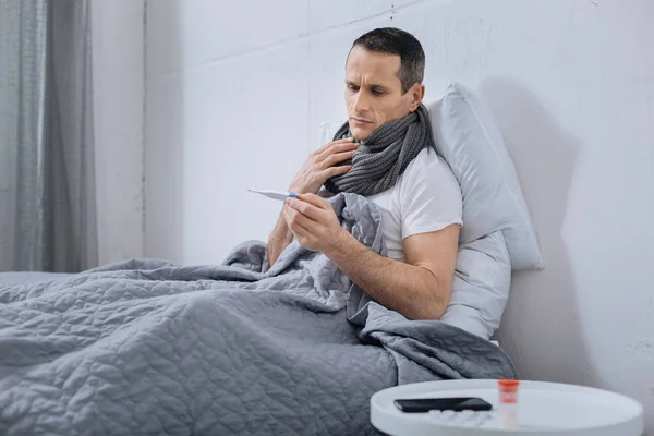 Hombre enfermo mirando el termómetro — Foto de Stock
