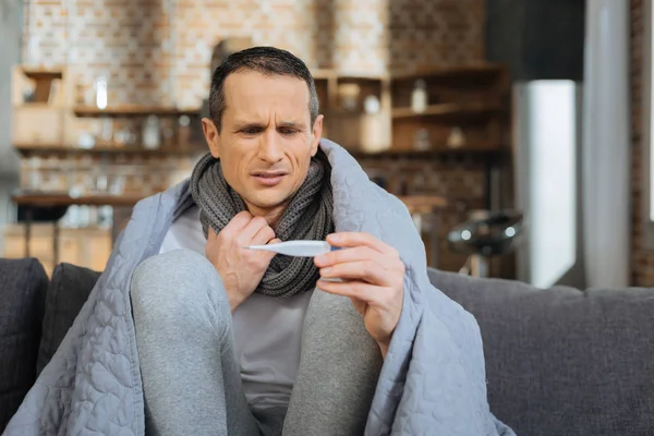 Aufmerksame männliche Person blickt auf ihr Thermometer — Stockfoto