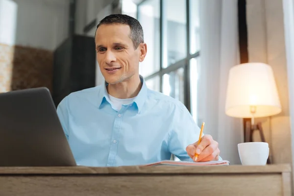Positiv entzückter Arbeiter beim Blick auf seinen Laptop — Stockfoto
