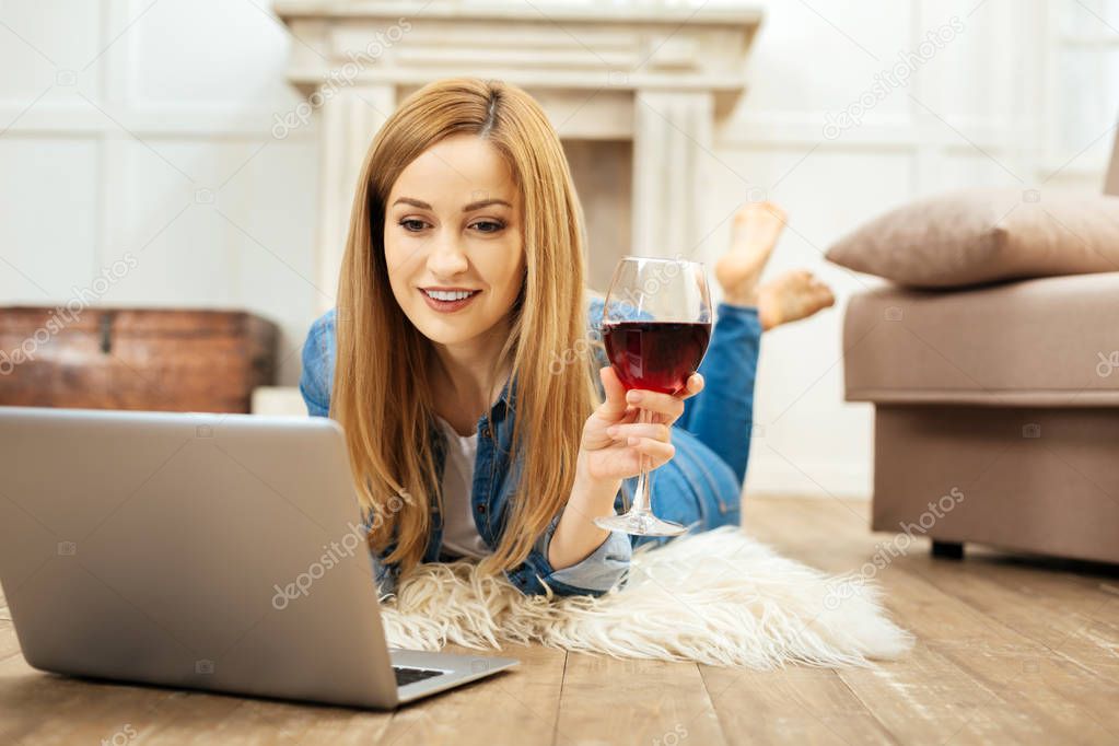 Joyful woman working and holding a glass of wine