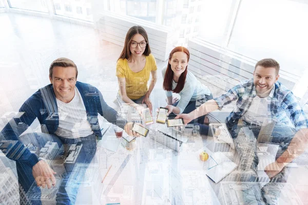 Compañeros sonrientes mostrando teléfonos móviles — Foto de Stock