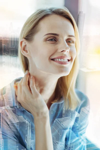 Pleasant kind woman holding hand near neck and smiling. — Stock Photo, Image