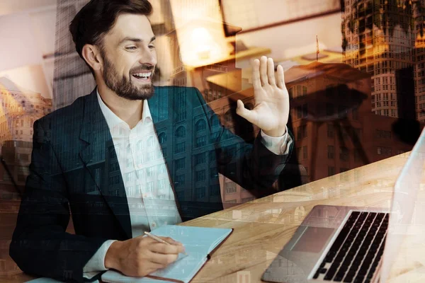 Fröhlicher Geschäftsmann grüßt seinen Gesprächspartner durch Webkamera — Stockfoto