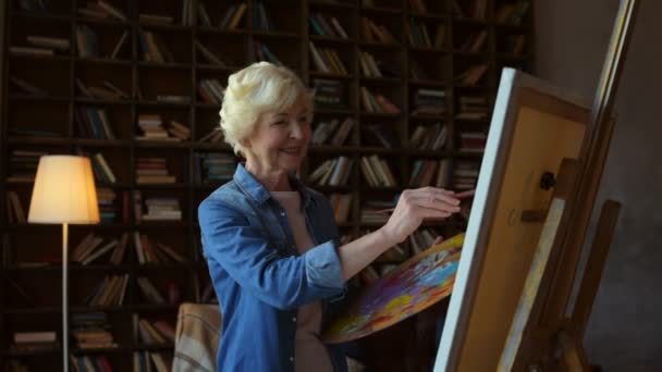 Веселая пожилая женщина рисует дома — стоковое видео