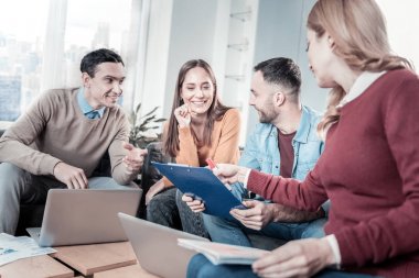 Oturma ve belge bakan keyifli neşeli çalışanlar.