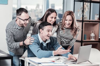 Neşeli hayran işçiler ayakta ve laptop arıyorum.