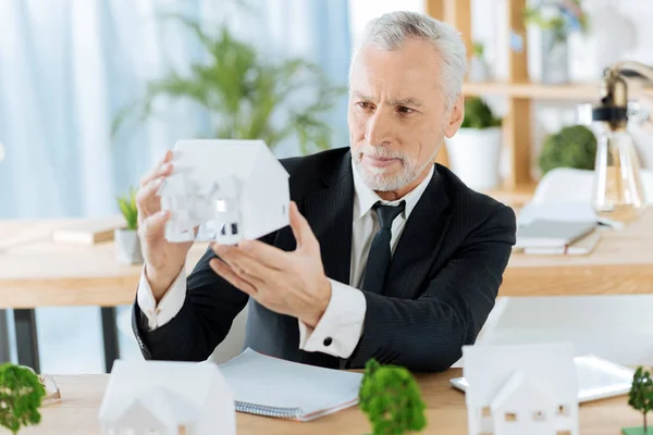 Empleado atento evaluando la miniatura de una buena casa —  Fotos de Stock