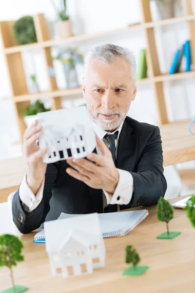 Zufriedener Immobilienmakler mit einer guten Miniatur eines echten Hauses — Stockfoto