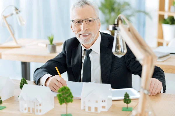 Ruhiger, fröhlicher Mann mit Brille, der lächelt und einen Bleistift in der Hand hält — Stockfoto