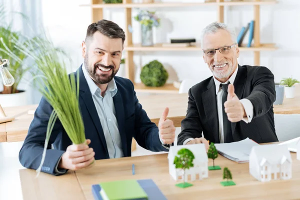 Confrères joyeux assis avec leurs pouces levés et souriant joyeusement — Photo