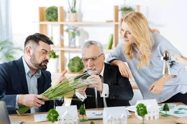 Curious colleagues touching a bunch of synthetic grass while discussing it — Stock Photo, Image