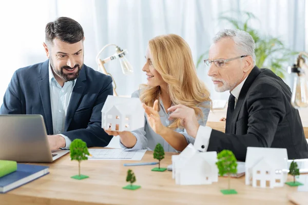 Emotionaler Mann blickt auf das Miniaturhaus, während sein Kollege es hält — Stockfoto