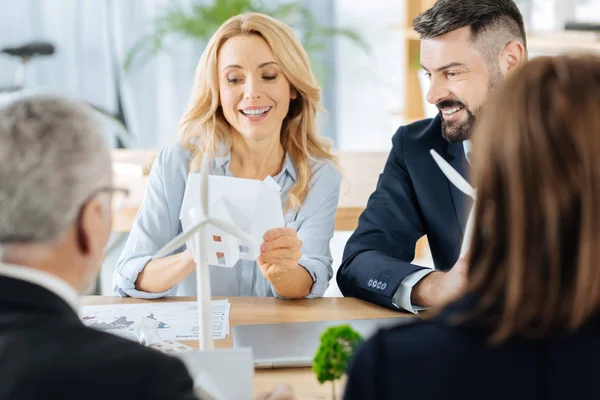 Smiling woman holding a tiny house while her colleague looking at it — Stock Photo, Image