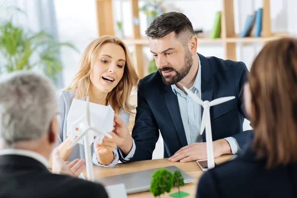 Emotional engineer holding a miniature house while explaining its peculiarities — Stock Photo, Image