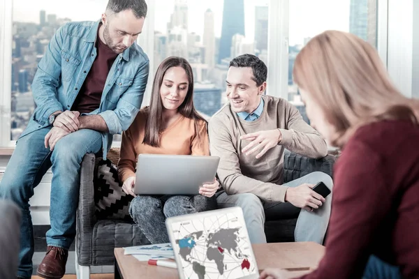 Trabajadores inteligentes y elegantes sentados juntos y usando computadoras portátiles . — Foto de Stock