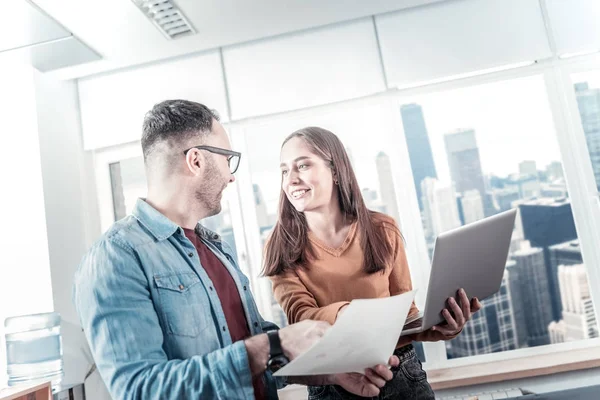 Vrolijke mooie vrouw permanent en houden haar laptop. — Stockfoto