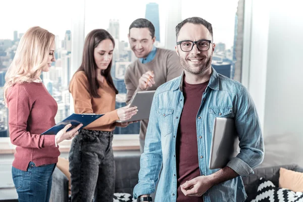 Hombre confiado con gafas mirando recto y sosteniendo el portátil . — Foto de Stock