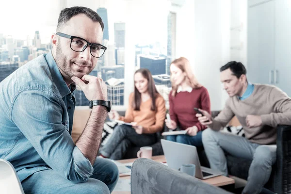 Agradable hombre con gafas sentado y agarrado de la mano cerca de la cabeza . — Foto de Stock