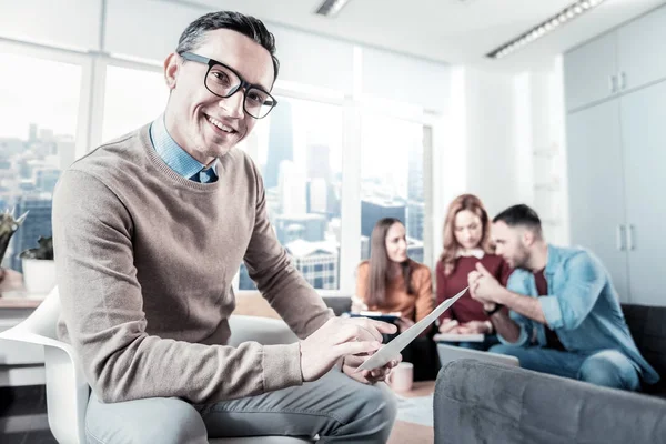 Alegre hombre con gafas sosteniendo el documento y mirando directamente . — Foto de Stock