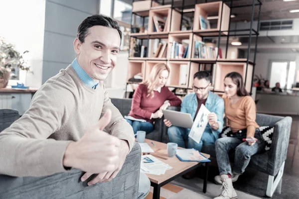 Hombre guapo satisfecho sentado y gesticulando . — Foto de Stock