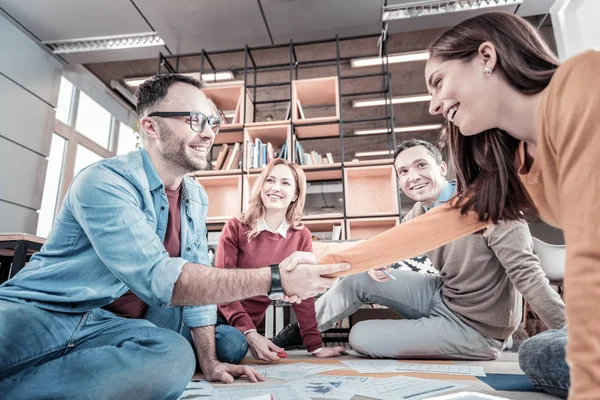 Empleados ocupados satisfechos sentados y estrechando las manos . — Foto de Stock