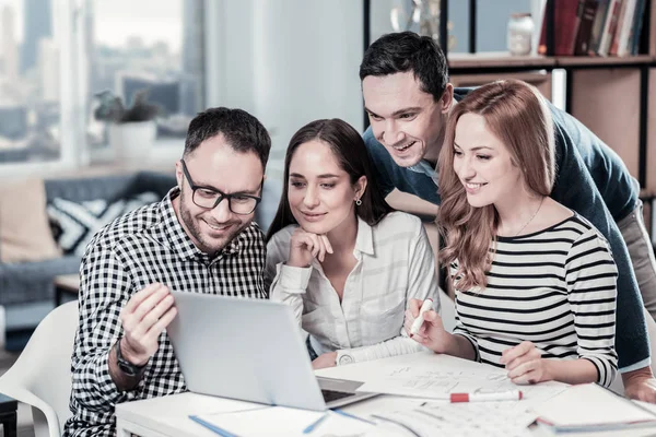 Empleados seguros satisfechos que se centran en la computadora portátil y hacen avisos . — Foto de Stock