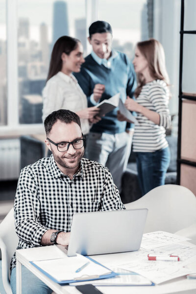 Мужчина в очках сидит и работает с ноутбуком
.