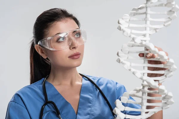 Medico donna riflettente che studia la struttura del DNA — Foto Stock