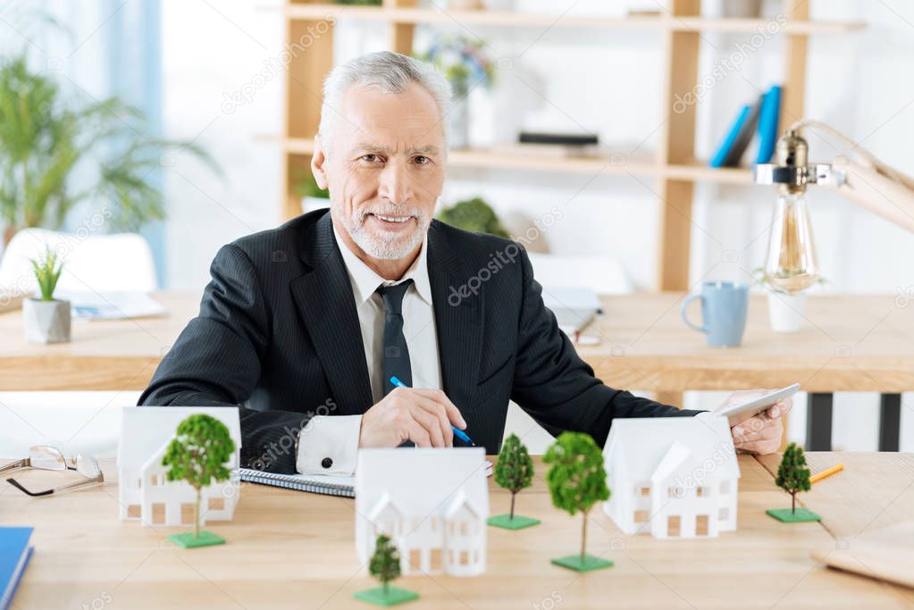 Pleasant real estate agent waiting for his colleagues while sitting alone