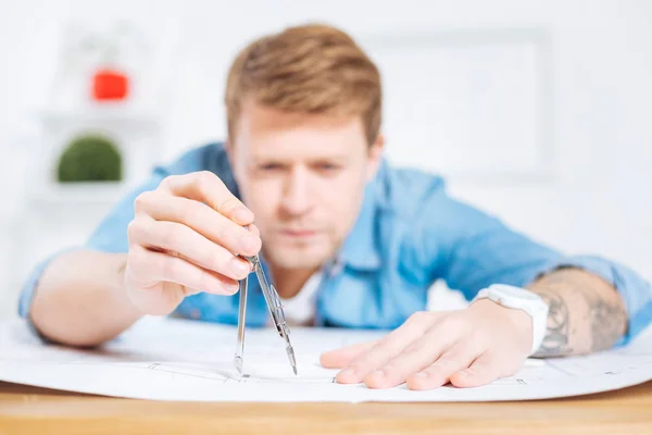 Busy engineer frowning while holding a pair of compasses — Stock Photo, Image