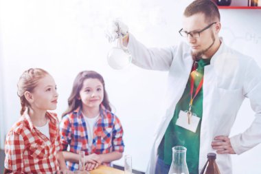 Çocuk dipli şişesi gösterilen komik profesyonel bilim adamı