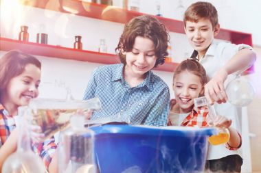 Heyecanlı öğrenciler kimyasal maddeler değişik sıvıların dev plastik kase içine dökme