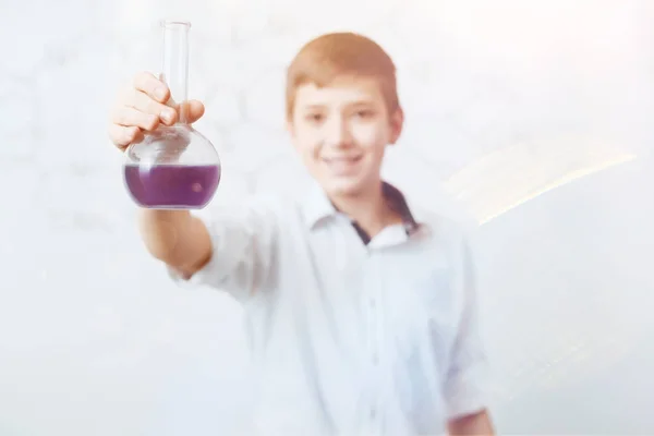 Smiling little scientist holding flask and posing for camera — Stock Photo, Image