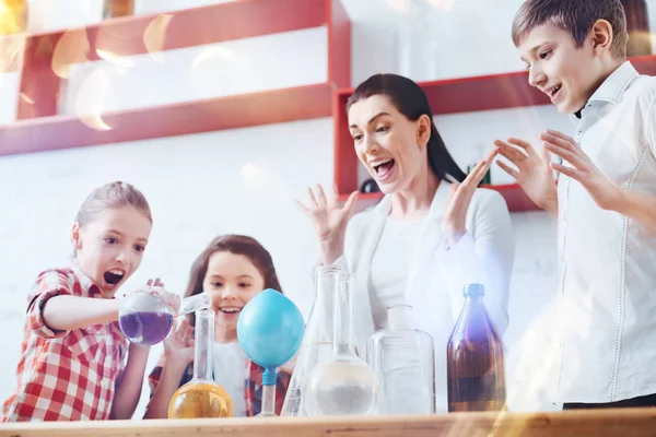 Zeer opgewonden kinderen en leraar vloeistoffen mengen tijdens scheikunde les — Stockfoto