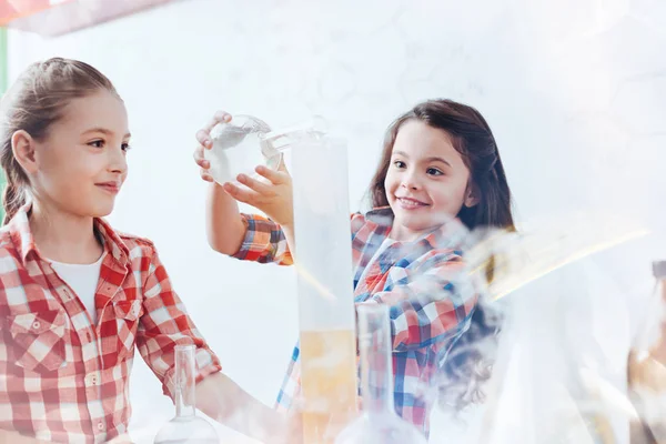 Vzrušený chytré dívky míchání kapalin během lekce chemie ve škole — Stock fotografie