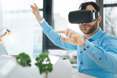 Gülümseyen mimar proje üzerinde çalışırken VR kulaklık kullanarak