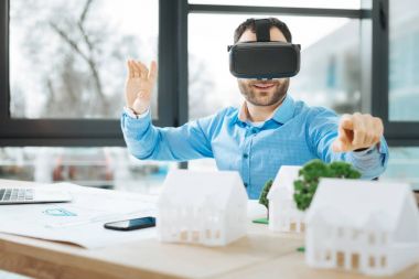 VR kulaklık giyen ve ev modelleri işaret yakışıklı mimar
