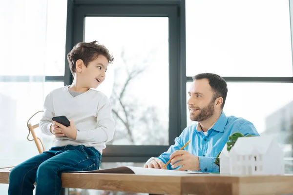 Маленький хлопчик розмовляє з батьком під час роботи над відбитками — стокове фото