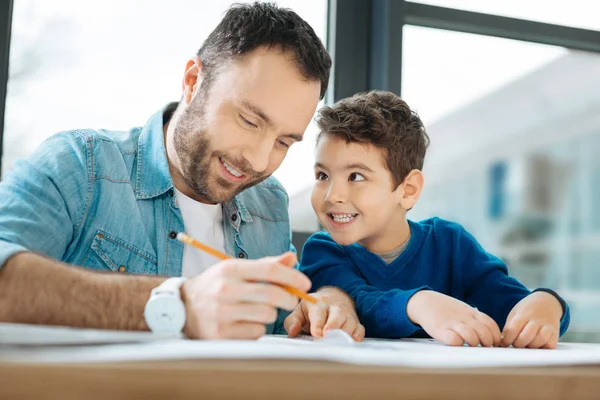 Alegre niño sonriendo a padre dibujando un plano — Foto de Stock