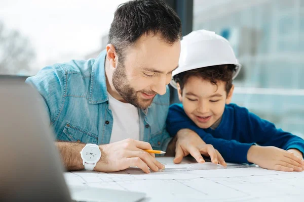 Happy father showing his son how to draw a blueprint — Stock Photo, Image